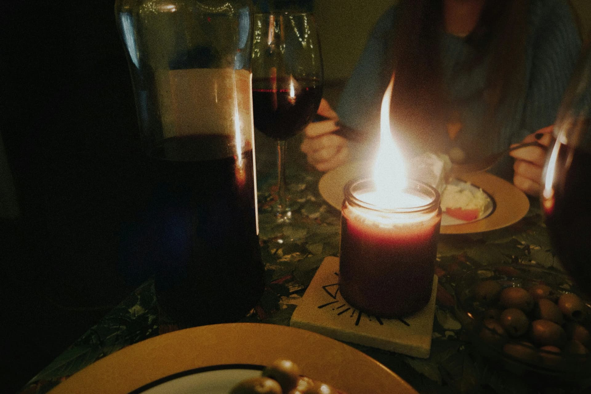 Close up of candlelit dinner table with wine and plates