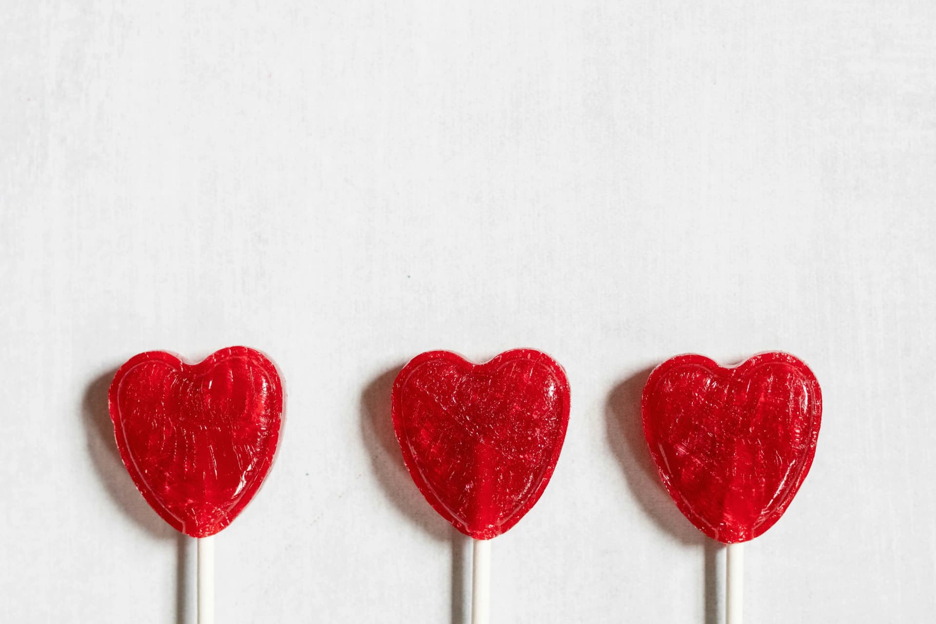 Three red heart-shaped lollipops
