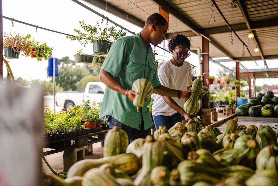 Couple laughing and picking out gourds at an outdoor farmers market stall
