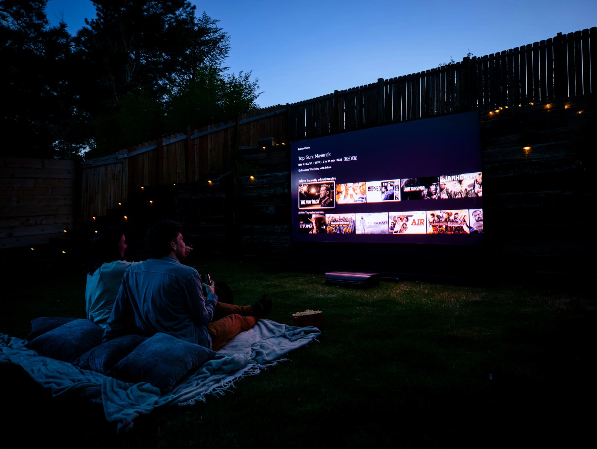 Couple spending their movie night outdoors on a projector in their backyard