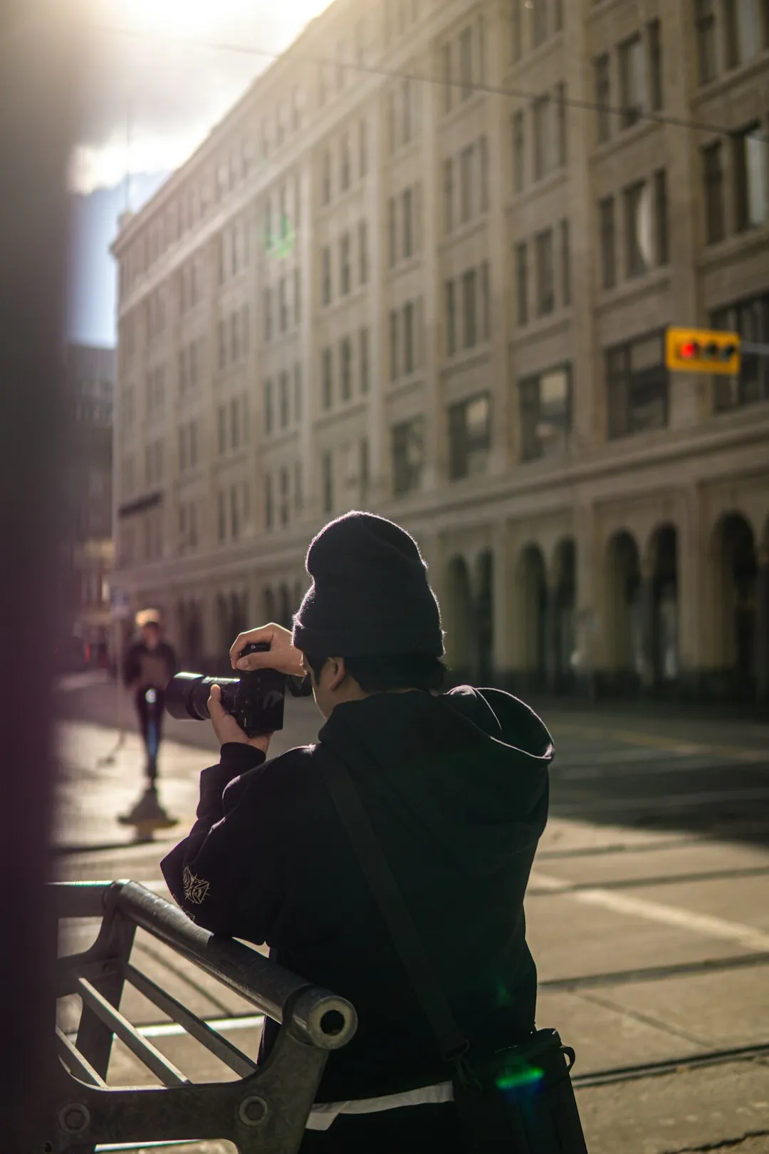 Person holding a camera on a city street in morning light