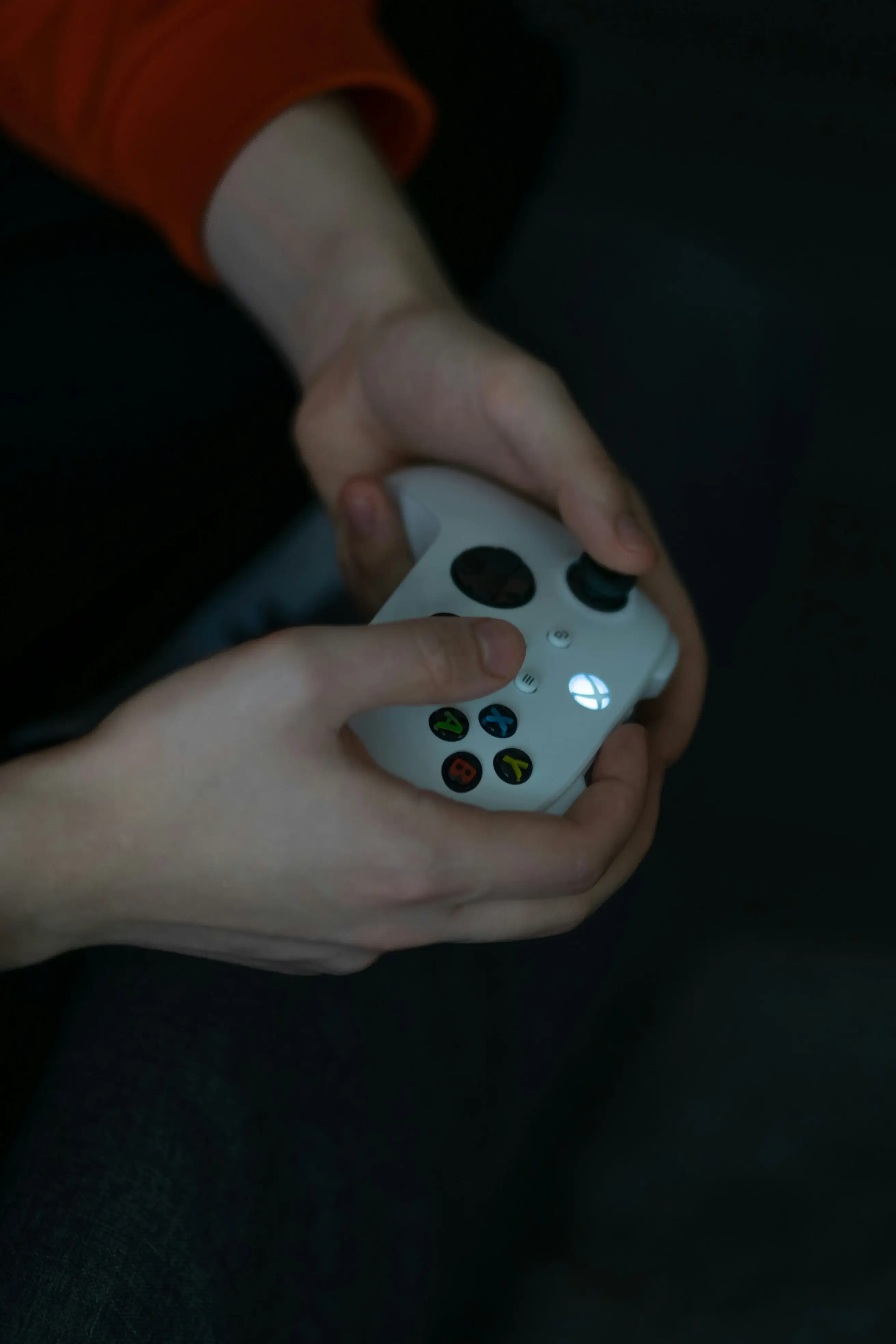 Close-up of hands holding illuminated Xbox controller