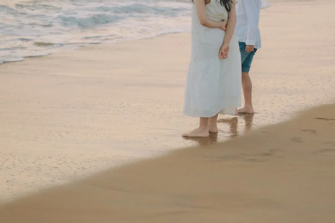 Couple standing on a wet sandy beach at sunset