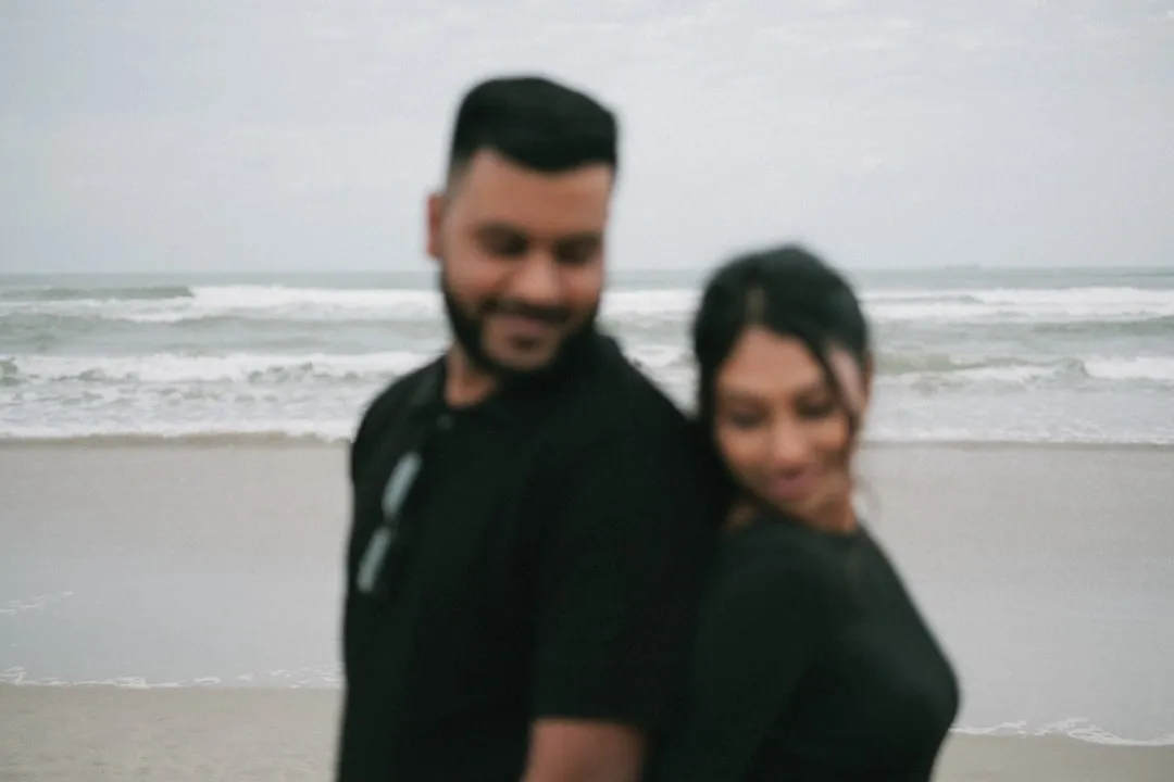 Couple standing back to back on the beach